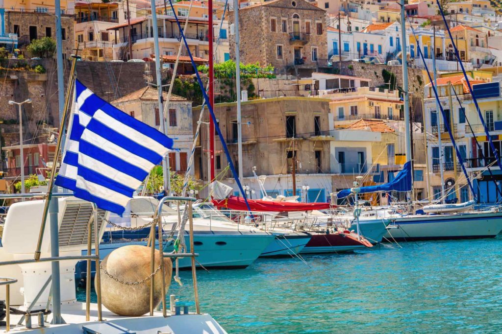 Blaue weiße griechische Flagge und Wind im griechischen Hafen voller Boote, Kos, Griechenland